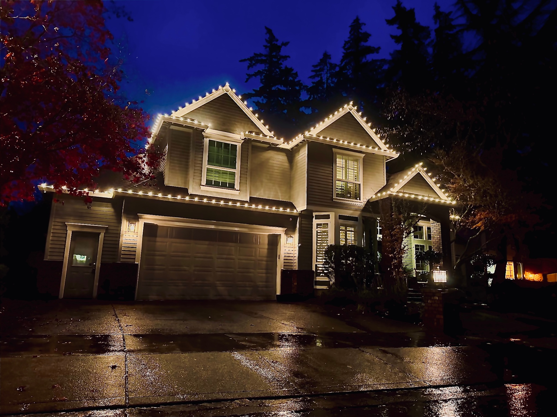 Classic warm white C9 roofline install on a two-story Portland home at dusk