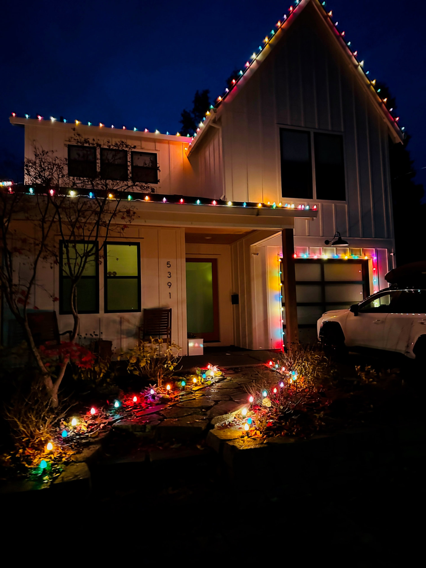 Multicolor C9 roofline and pathway lighting on a modern farmhouse